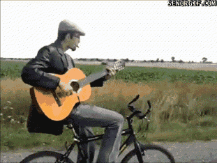 Guy playing harmonica and guitar while riding bicycle